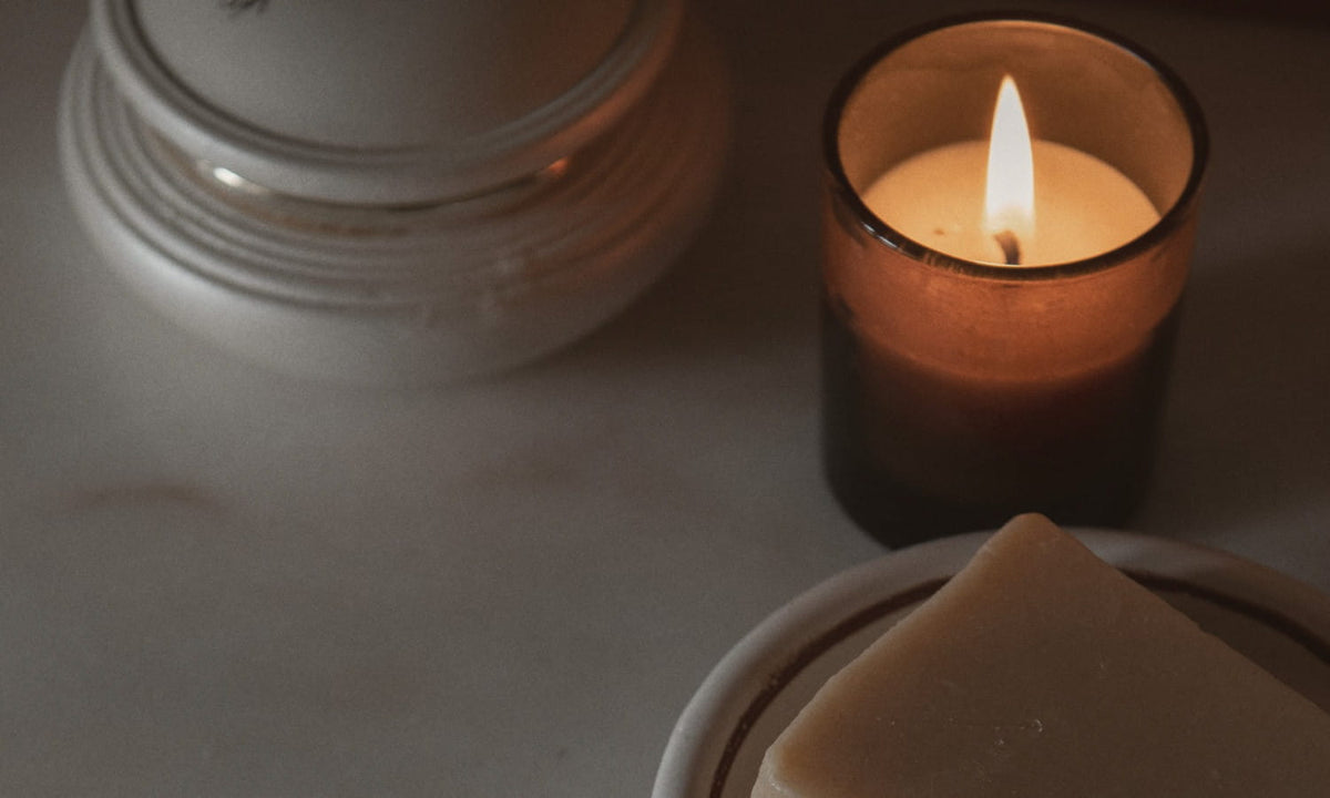 Bougie allumée dans un verre ambré près d'un pain de savon