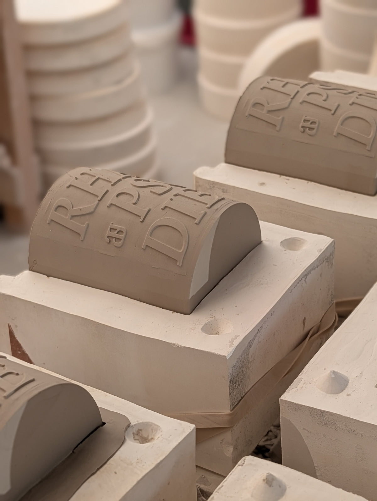 Pièces de céramique en cours de fabrication dans l'atelier de l'Ain, le mot Rhapsodie en relief