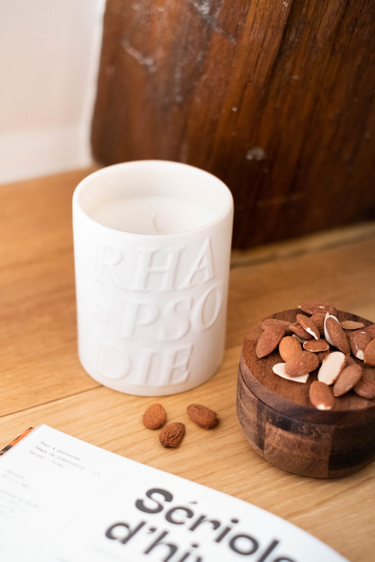 Bougie Amara à côté d'un bol d'amandes, sur une table en bois
