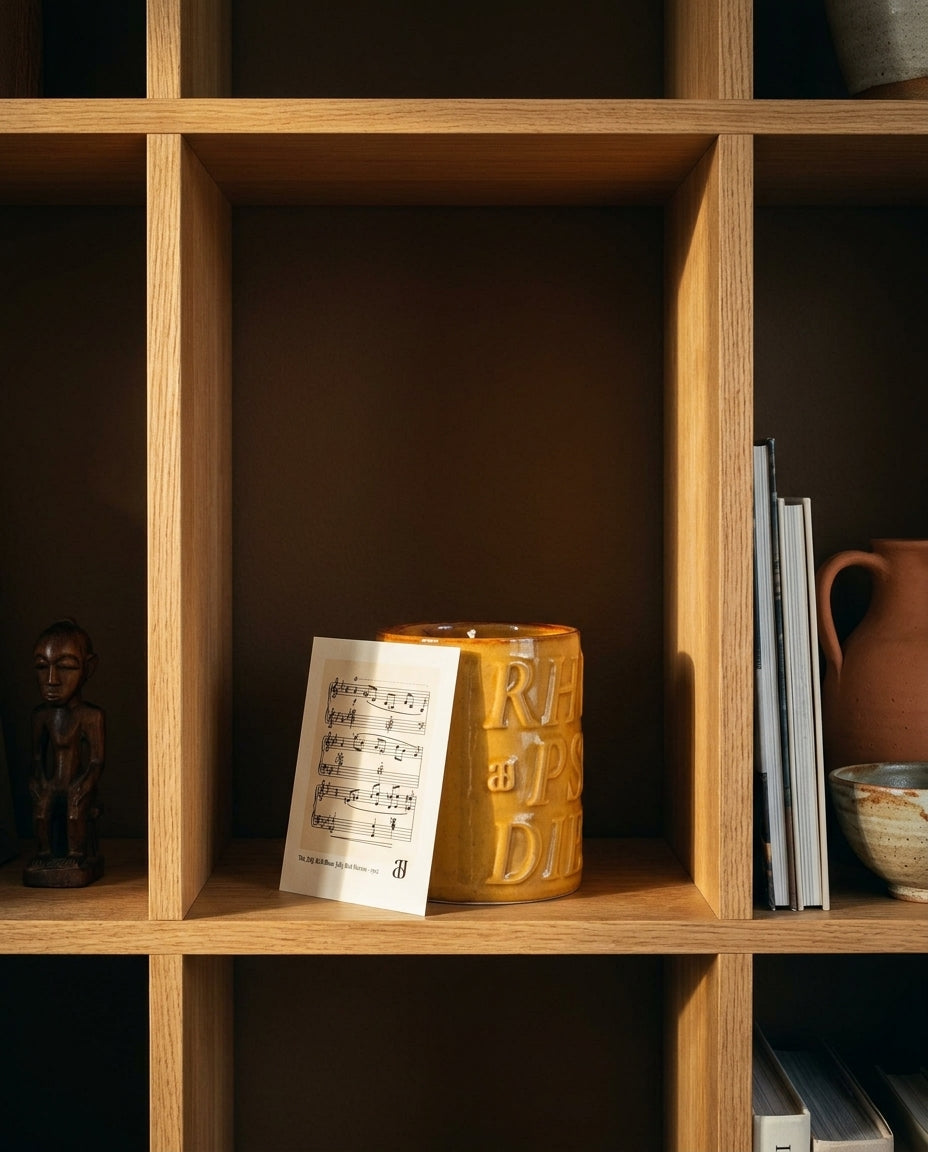 Bougie Rhapsodie Bourbon sur une étagère, avec son feuillet de partition.