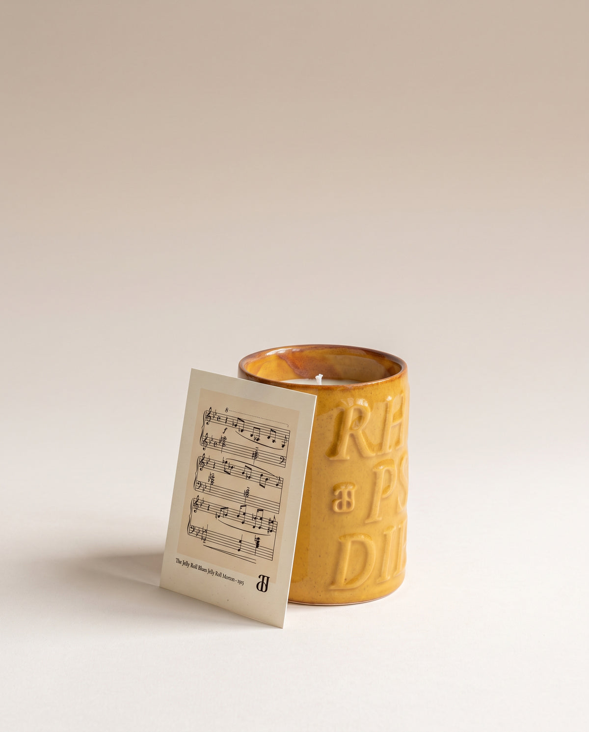Bougie Bourbon dans sa céramique émaillée jaune miel, avec le feuillet de la partition de Jelly Roll Morton