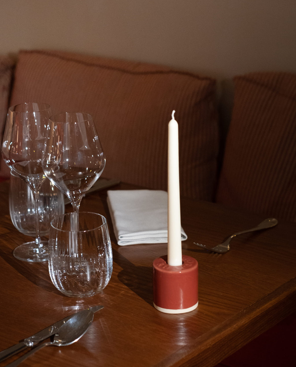 Bougeoir Véraison et sa chandelle blanche sur une table de restaurant, près de verres à vin