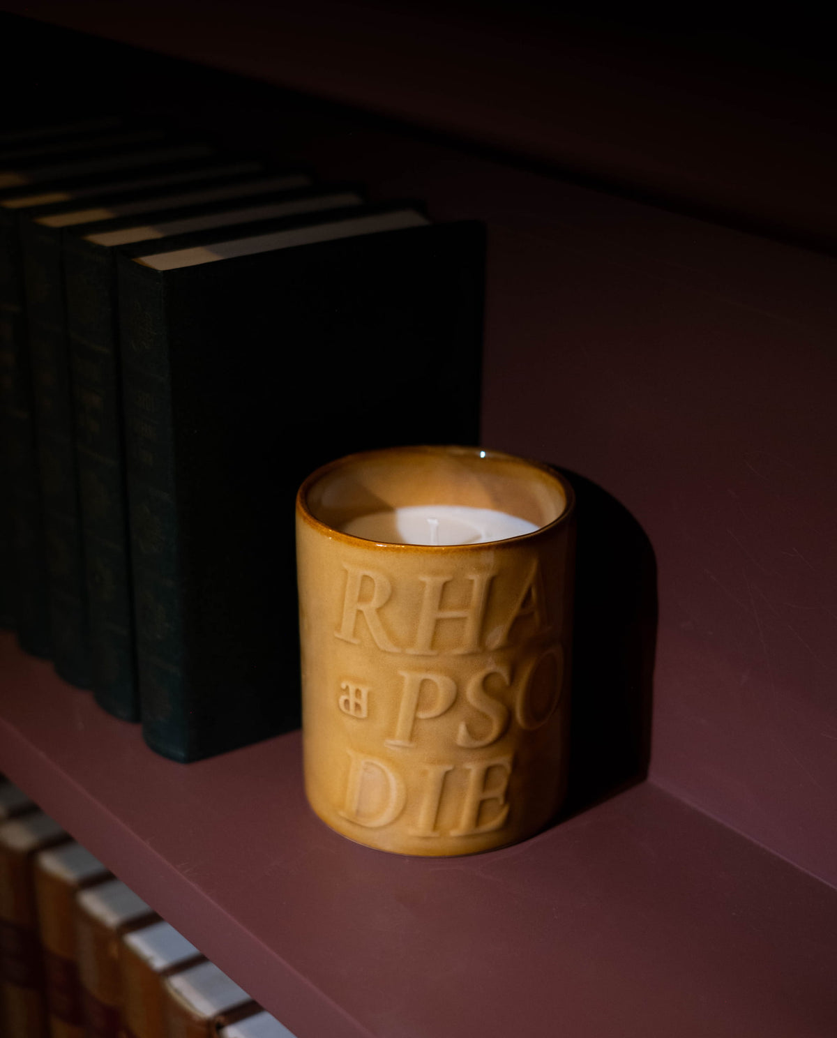 Bougie Bourbon sur une étagère sombre, près de livres