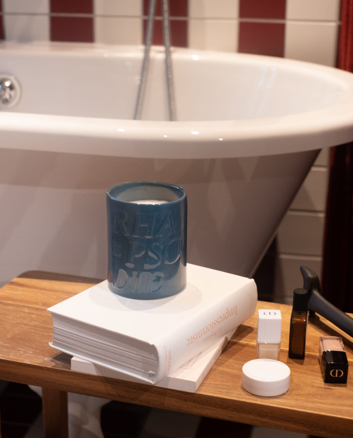 Bougie Riviera posée sur des livres au bord d'une baignoire